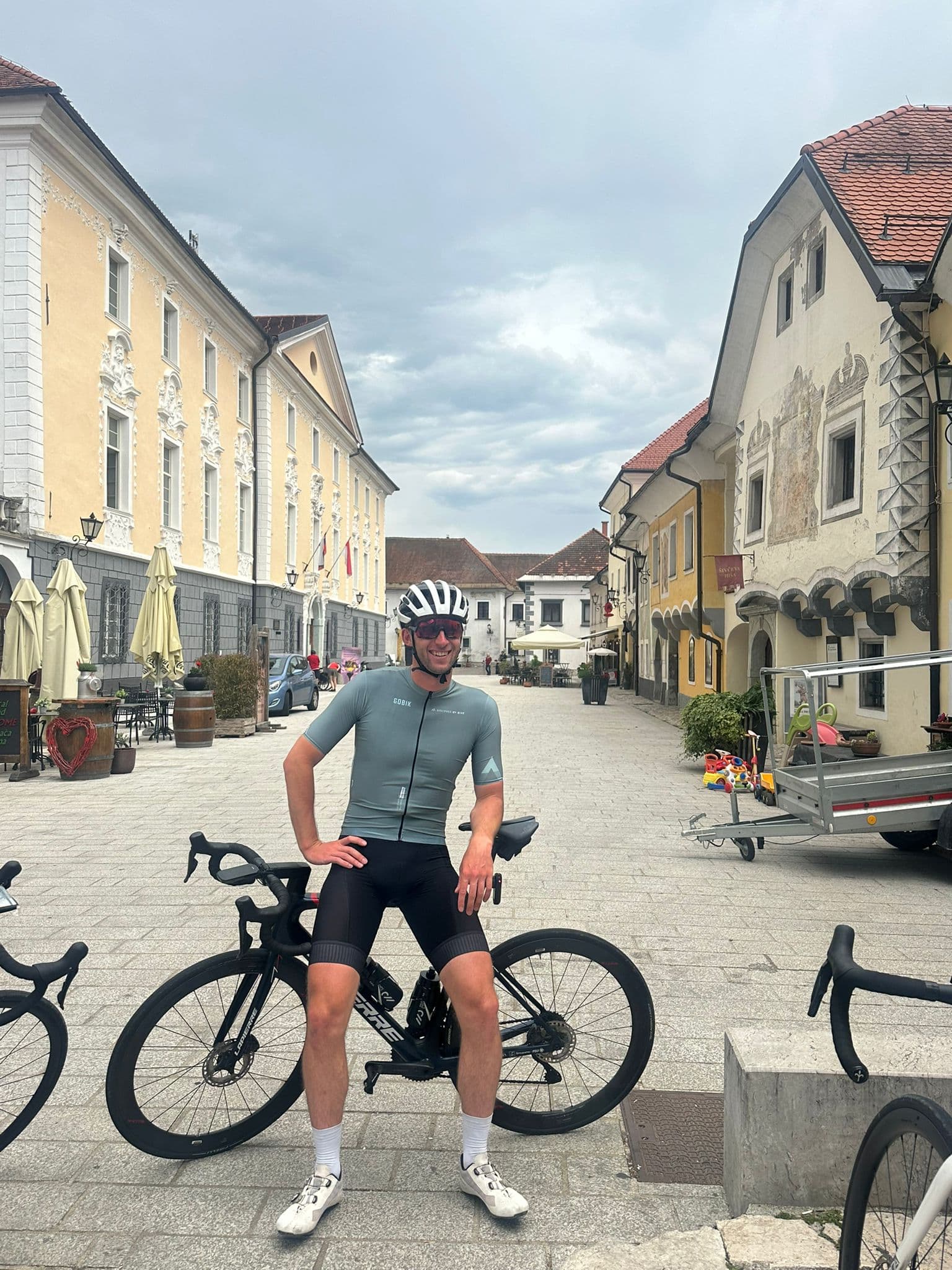 Cyclist resting on road bike in Radovljica town square with historic buildings.