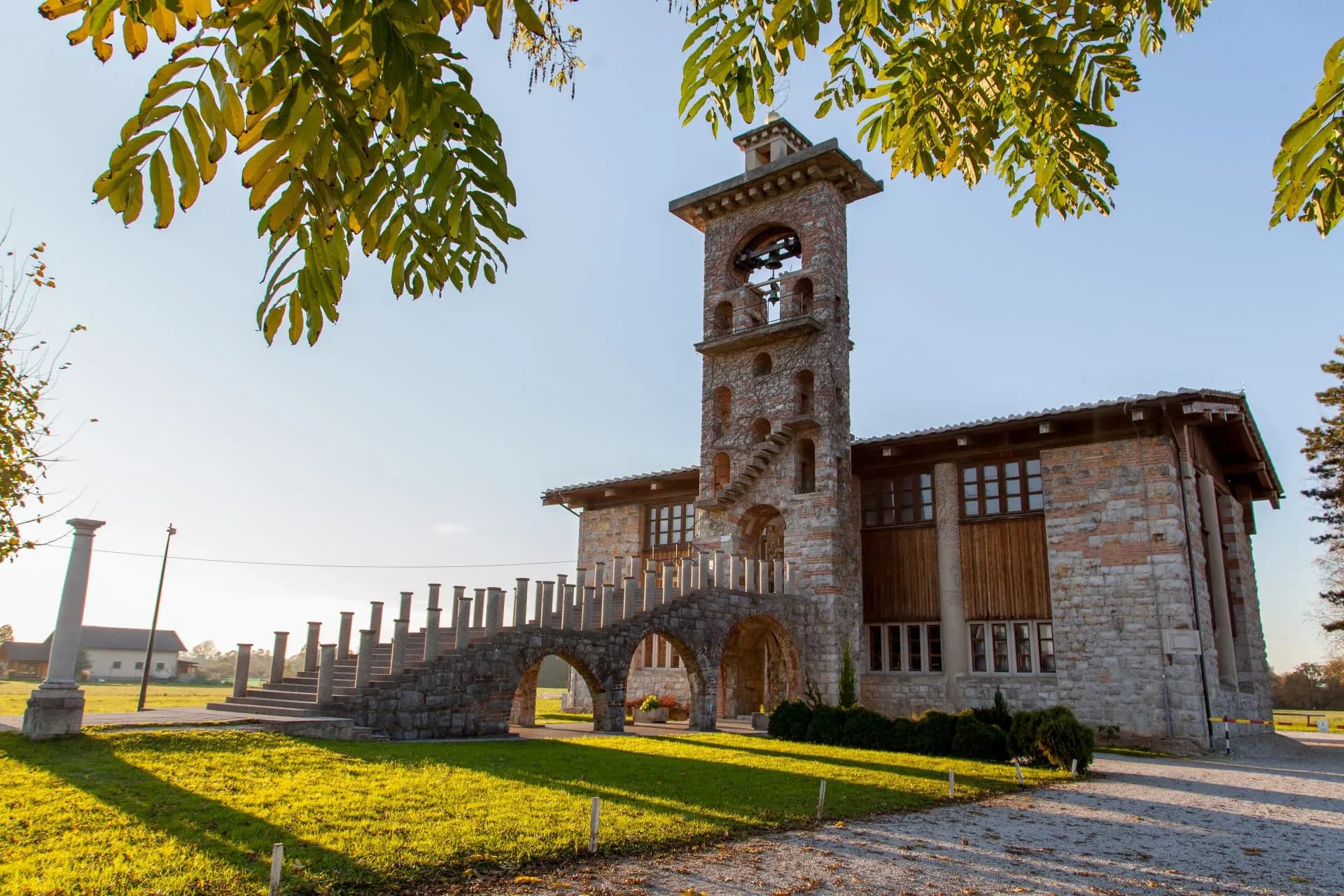 Stone church building with bell tower and arched stone staircase on sunny day